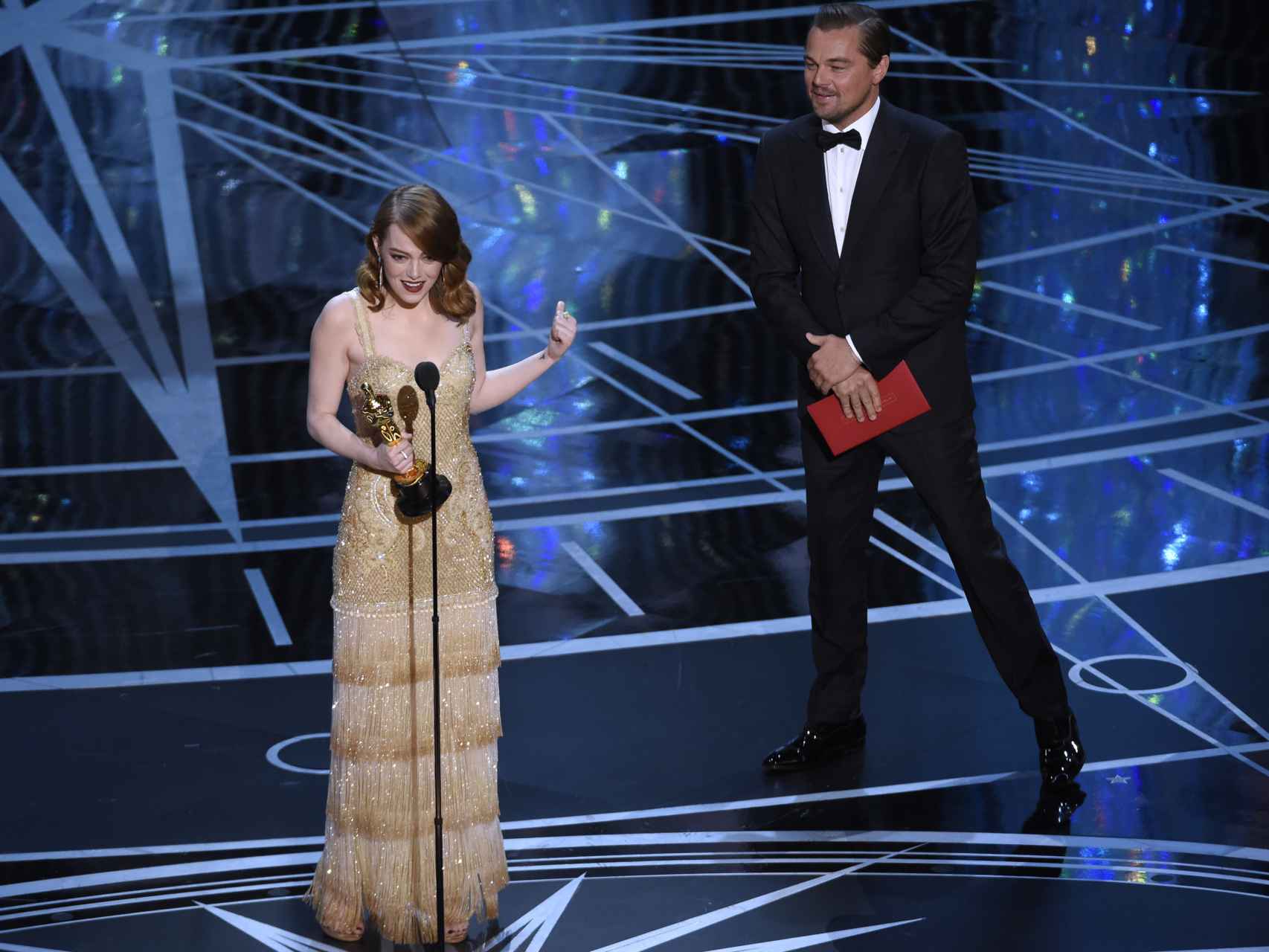 Leonardo DiCaprio entrega a Emma Stone el premio que ganó él el año pasado.
