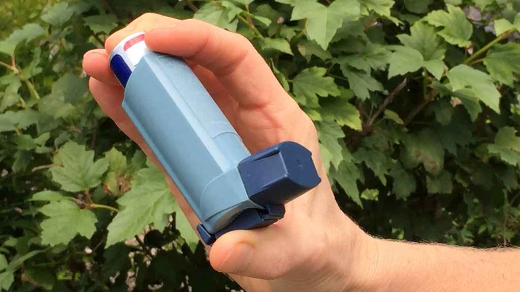 Una persona sostiene su inhalador para el asma.