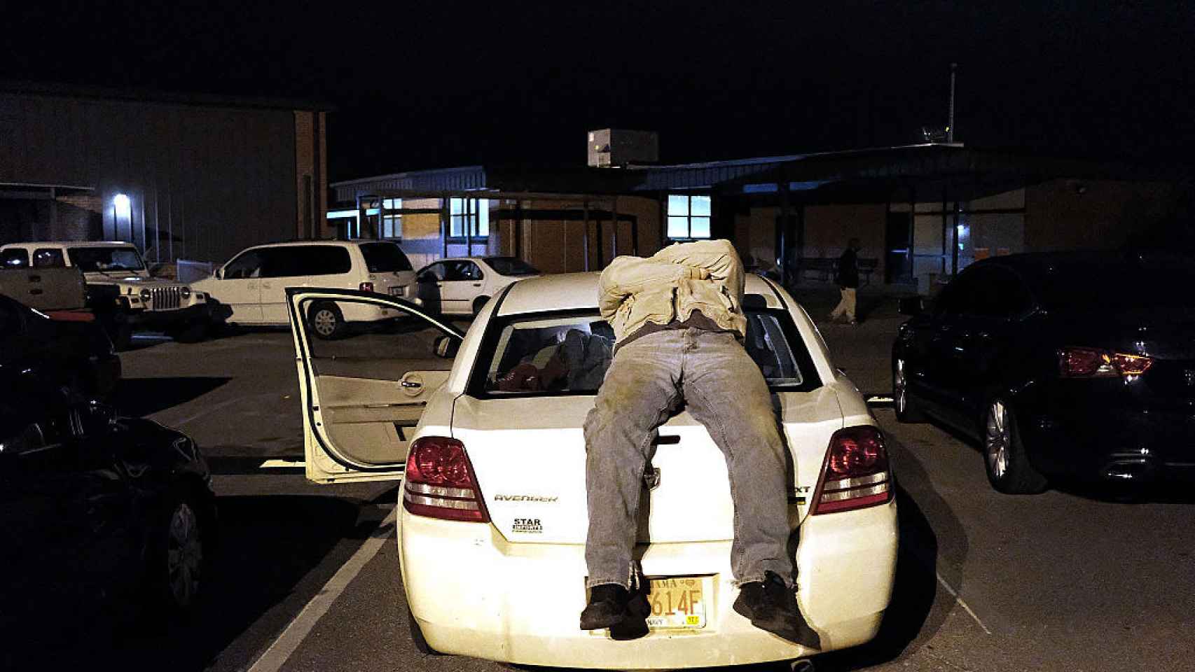 Un hombre duerme sobre su coche en Milton, Florida.