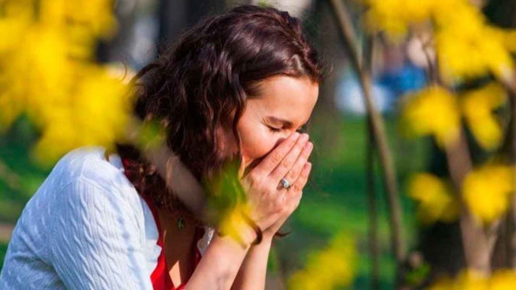 Una mujer se tapa la nariz y la boca para estornudar.
