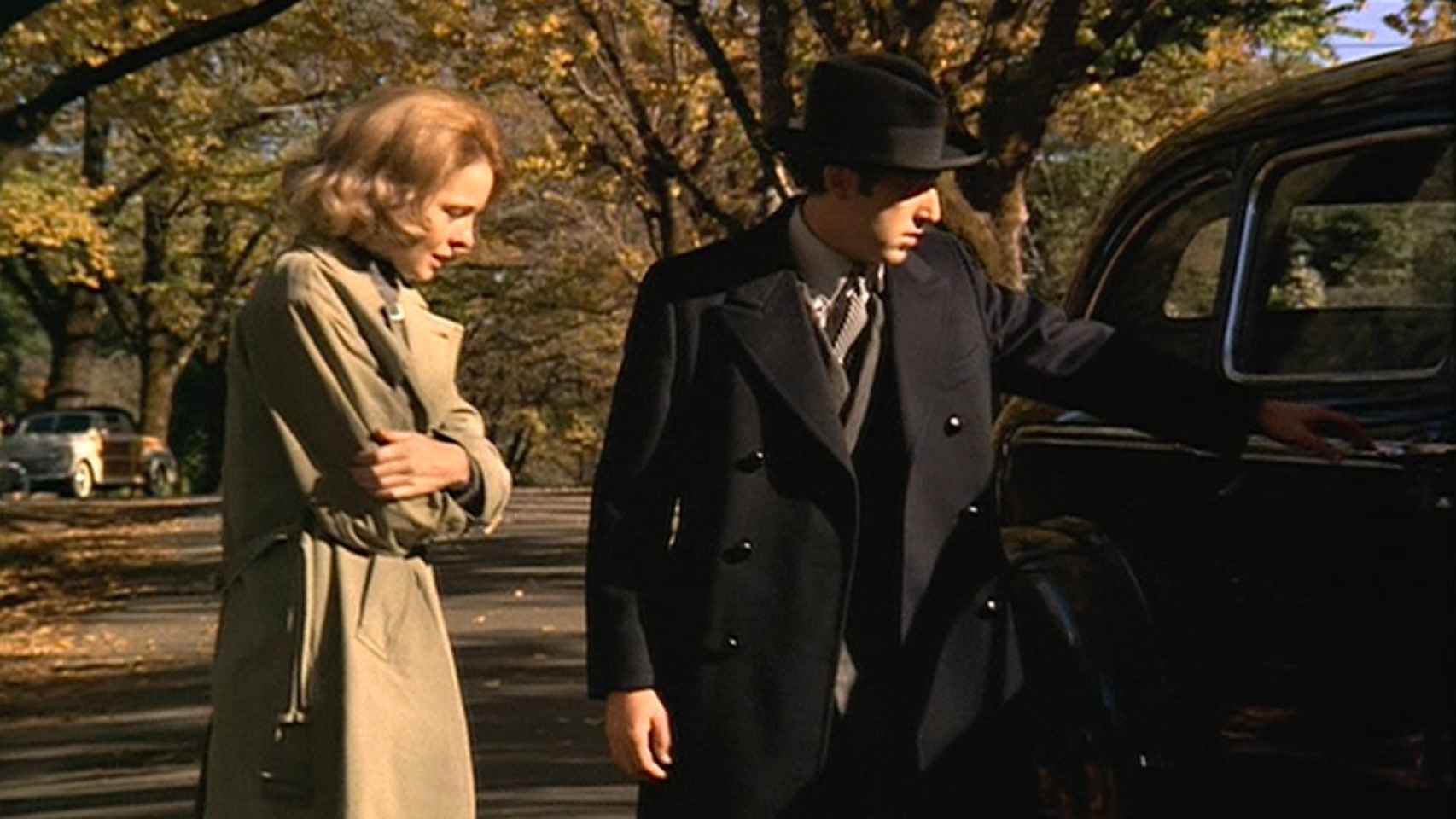 Michael Corleone con un traje gris de raya diplomática y un abrigo negro de doble botonadura, (El Padrino, 1972).