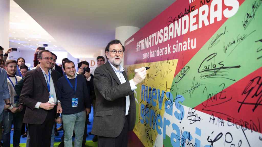 Rajoy firma en un mural durante el congreso del PP vasco.