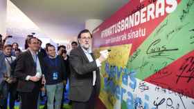 Rajoy firma en un mural durante el congreso del PP vasco.