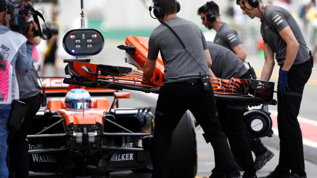 Mecánicos le cambian el alerón delantero a Fernando Alonso.