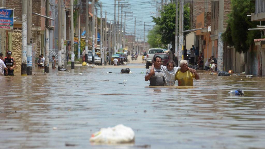 Los residentes de la ciudad de Piura, en Perú, tratan de cruzar una calle inundada.
