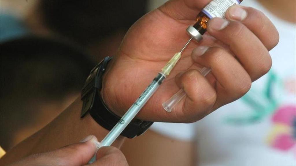 Un hombre prepara la inyección de una vacuna.