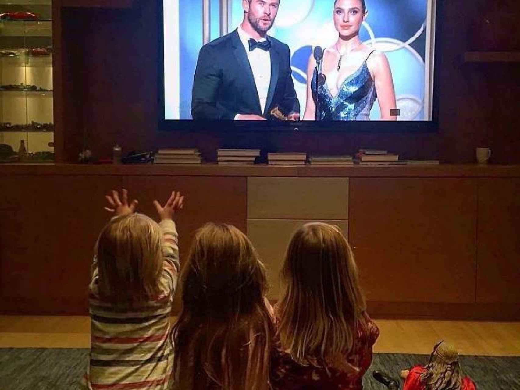 Los tres hijos del matrimonio viendo a su padre en la televisión.