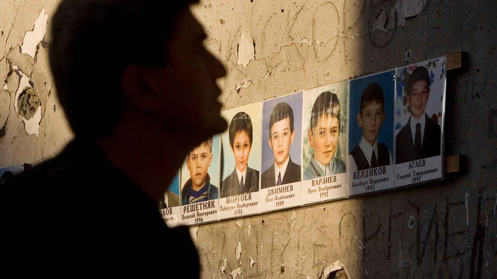 Un hombre junto a fotografías de algunas de las víctimas de la masacre en la escuela de Beslán