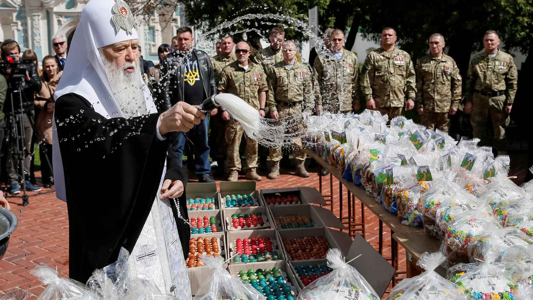 Un sacerdote de la Iglesia Ortoxoda de Ucrania vierte agua bendita sobre huevos de chocolate.