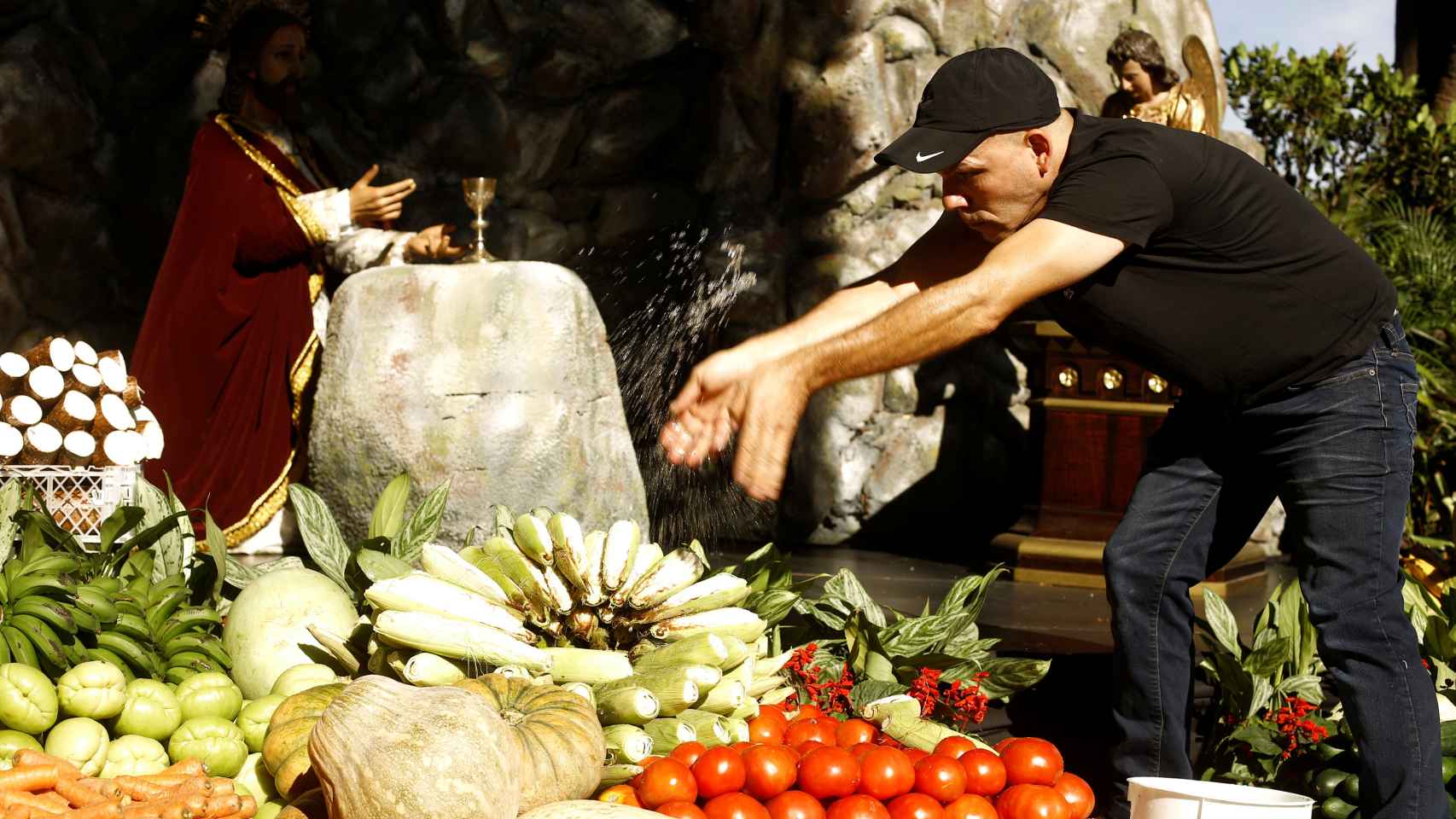 Hombre en Costa Rica vierte agua bendita sobre verduras donadas a los necesitados.