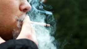 Un hombre fuma un cigarro de tabaco.