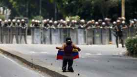 Una manifestante, de rodillas frente  al cordón policial en Caracas