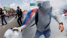 Un manifestante opositor devuelve una lata de gas lanzada por las fuerzas de seguridad.