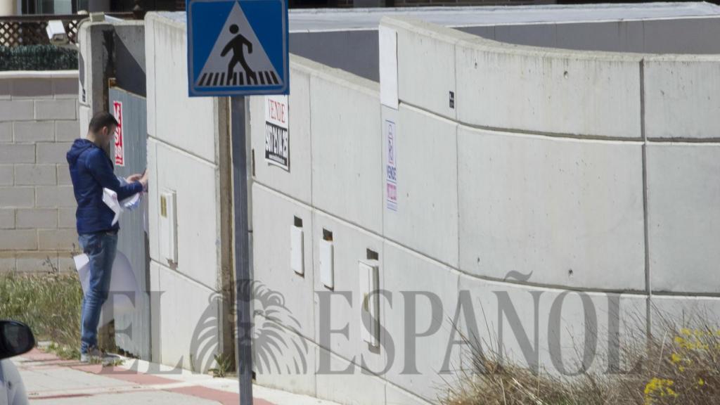 Un agente inmobiliario poniendo un nuevo cartel a la vivienda.