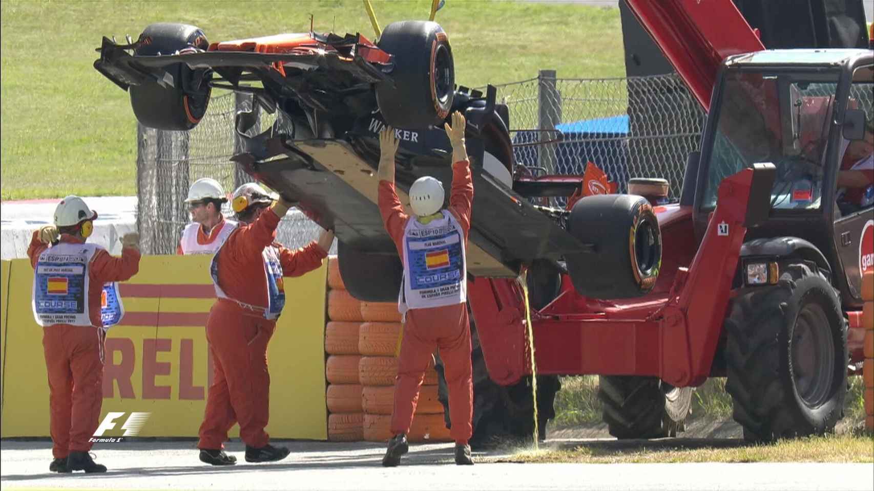 Los operarios retirando el coche de Alonso tras dos curvas.