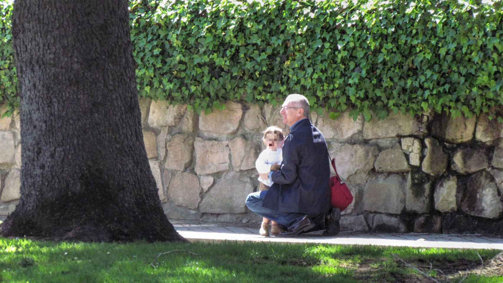 Gallardón se agacha para coger a su nieto en brazos.