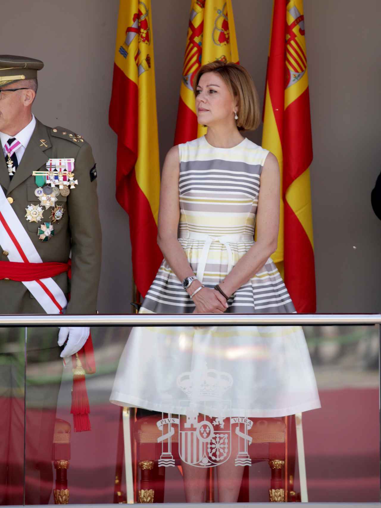 La ministra de Defensa, María Dolores Cospedal, ha llevado un vestido beige con vuelo en la falda y rayas.