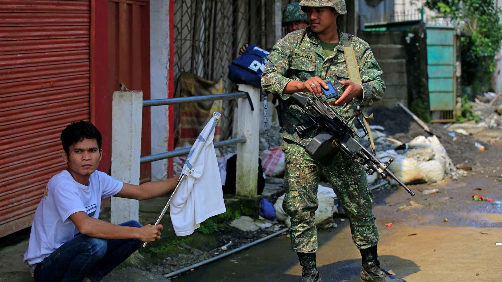 Un civil con una bandera blanca junto a un soldado filipino en Marawi