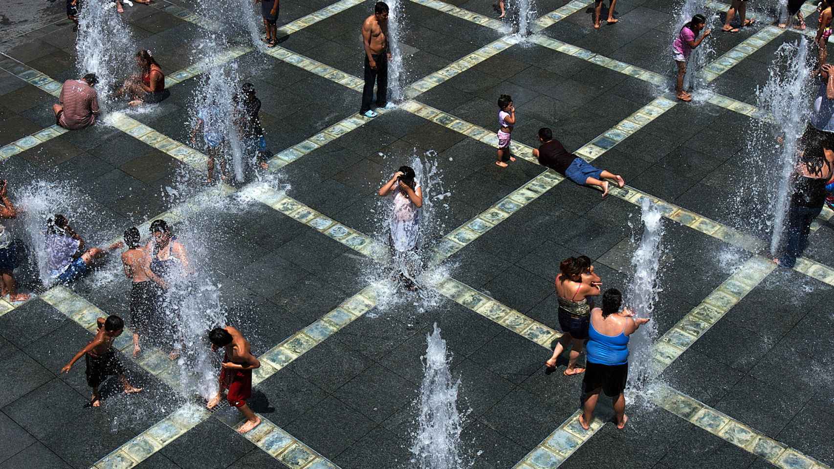 Gente resfrescándose en una fuente.