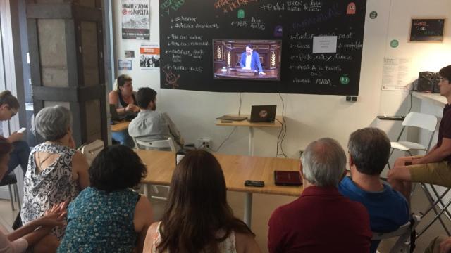 Varios de los asistentes ven en la tele la intervención de Iglesias.