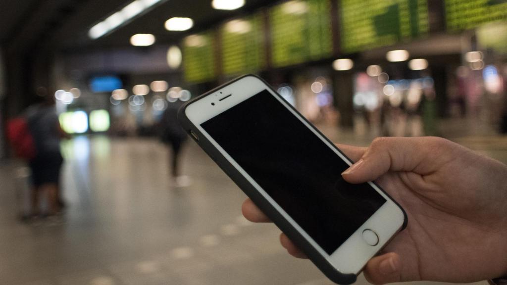 Una joven utiliza su móvil en una estación de tren.