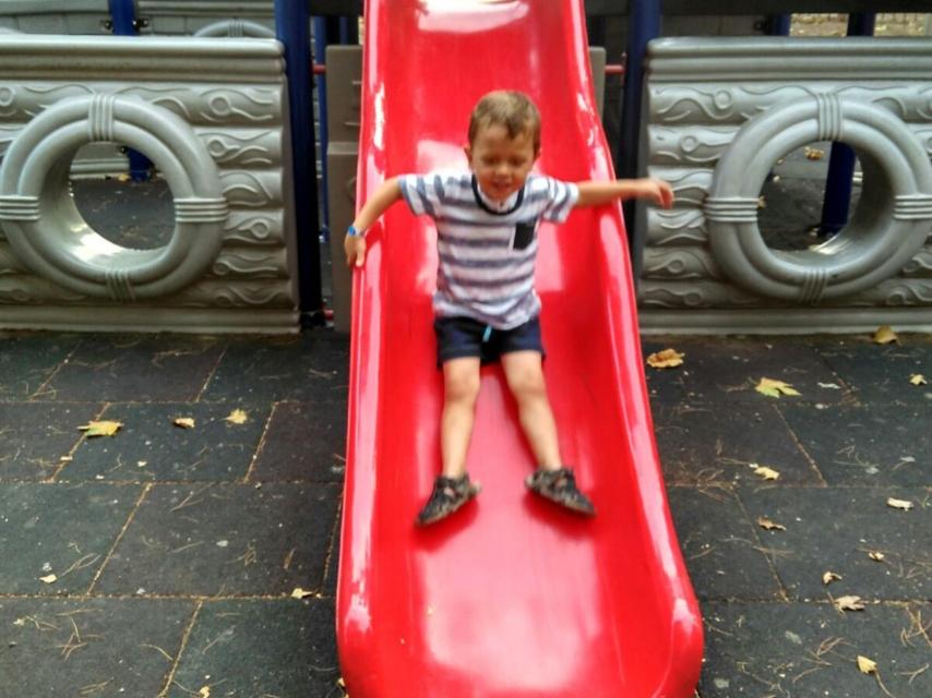 Víctor jugando en el tobogán de un parque.