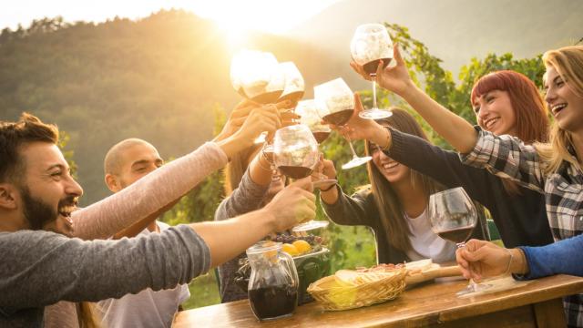 Happy friends having fun an drinking wine in autumn time