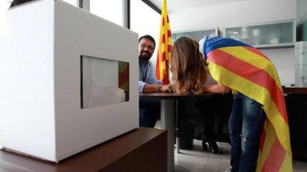 Una joven con la bandera independentista vota en una urna el 9N.