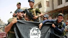 Soldados de Irak hacen el símbolo de la victoria con una bandera del ISIS en Mosul