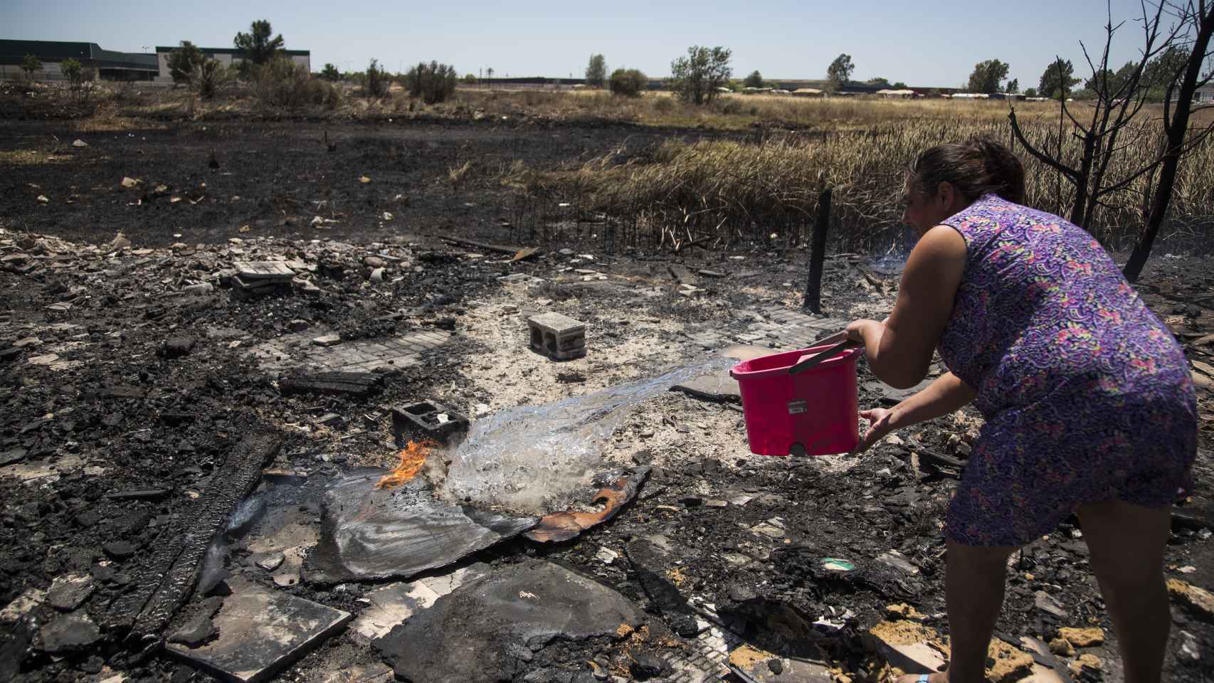 Chabolistas refrescando la zona afectada por el incendio del día anterior que destruyó cuatro chabolas por temor a que vuelva a activarse. Foto: Fernando Ruso