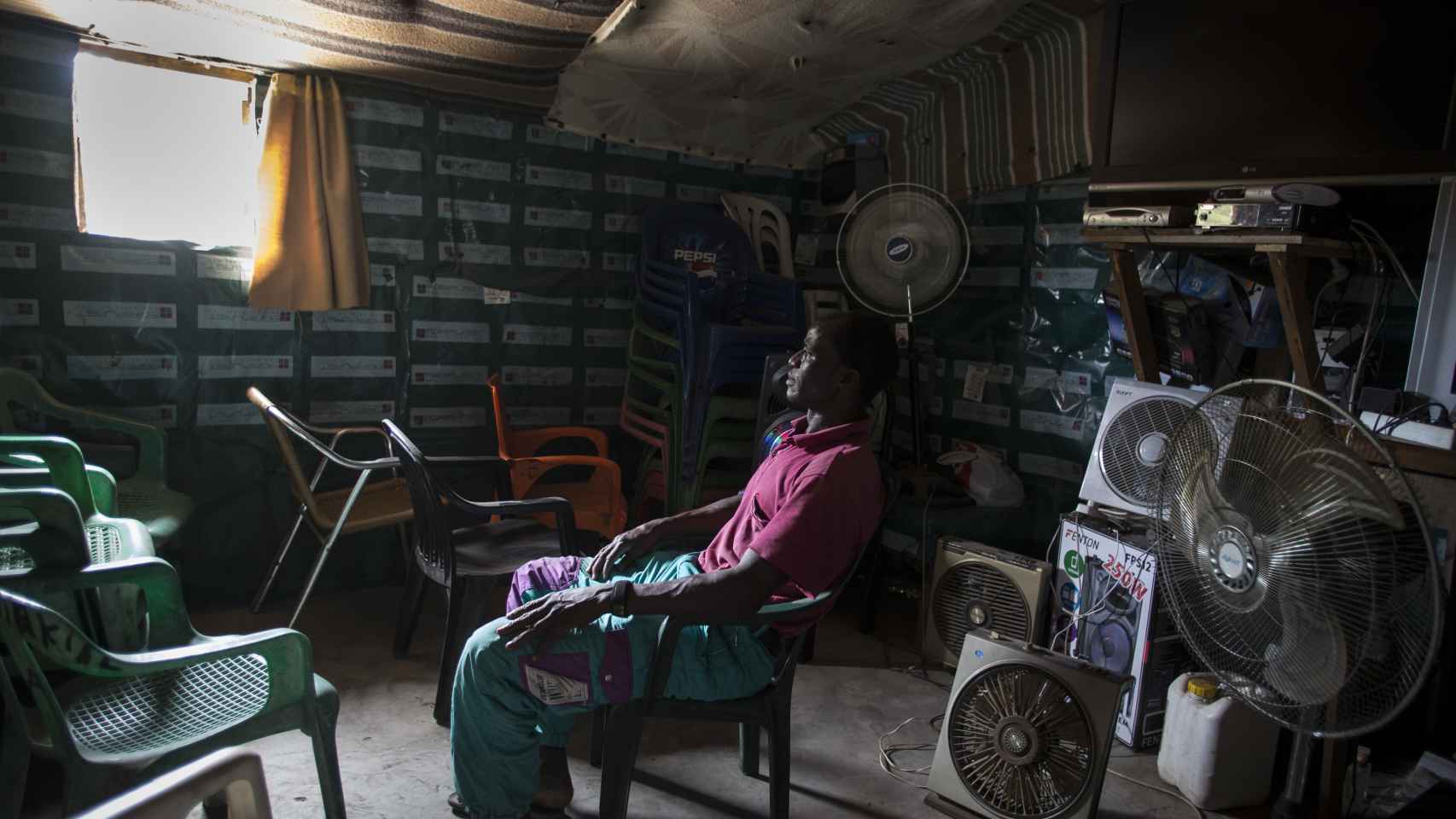 Issa Diakite Di Biletti en el interior de la sala de ocio que ha construido en el poblado y que cuenta con multitud de ventiladores y un televisor. Foto: Fernando Ruso