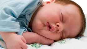 Un bebé duerme plácidamente mientras su madre busca la sillita eléctrica.