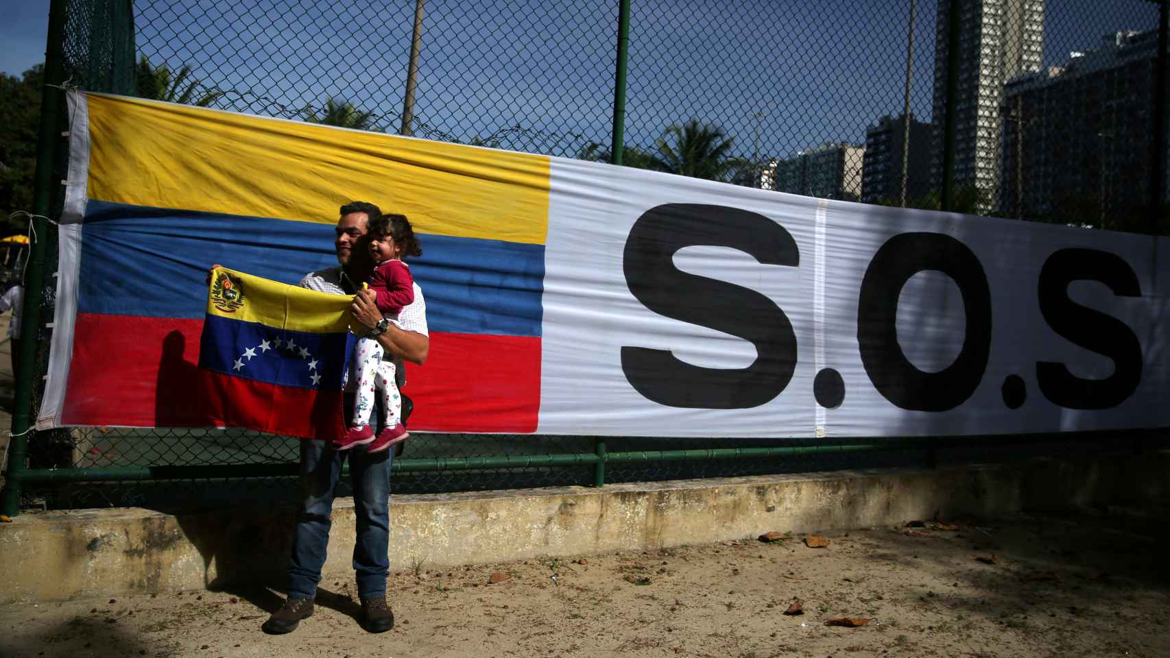 Un hombre posa con su hija y la bandera de Venezuela.