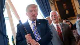 Trump sostiene un bate de béisbol ante la mirada de su vicepresidente, Mike Pence.