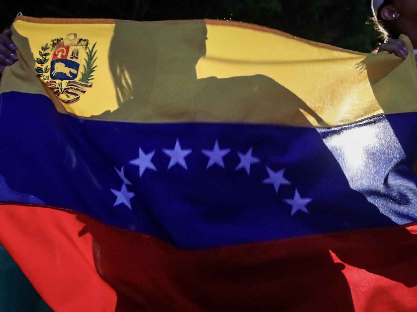 Un opositor levanta la bandera de Venezuela tras la consulta plebiscitaria.