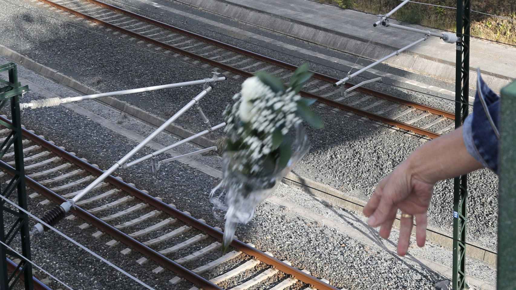 Un familiar de las víctimas arroja flores en la curva de Angrois.