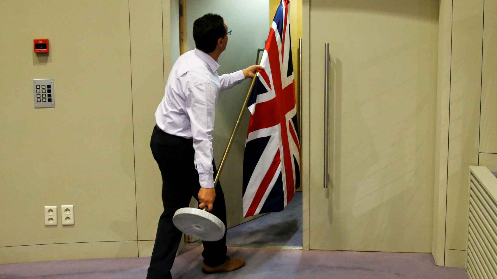 Un funcionario retira la bandera de Reino Unido en la Comisión