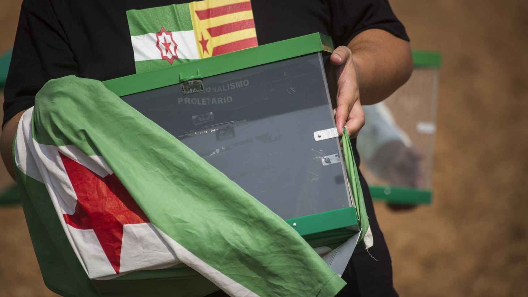 Una urna envuelta en la bandera de Andalucía con una estrella roja