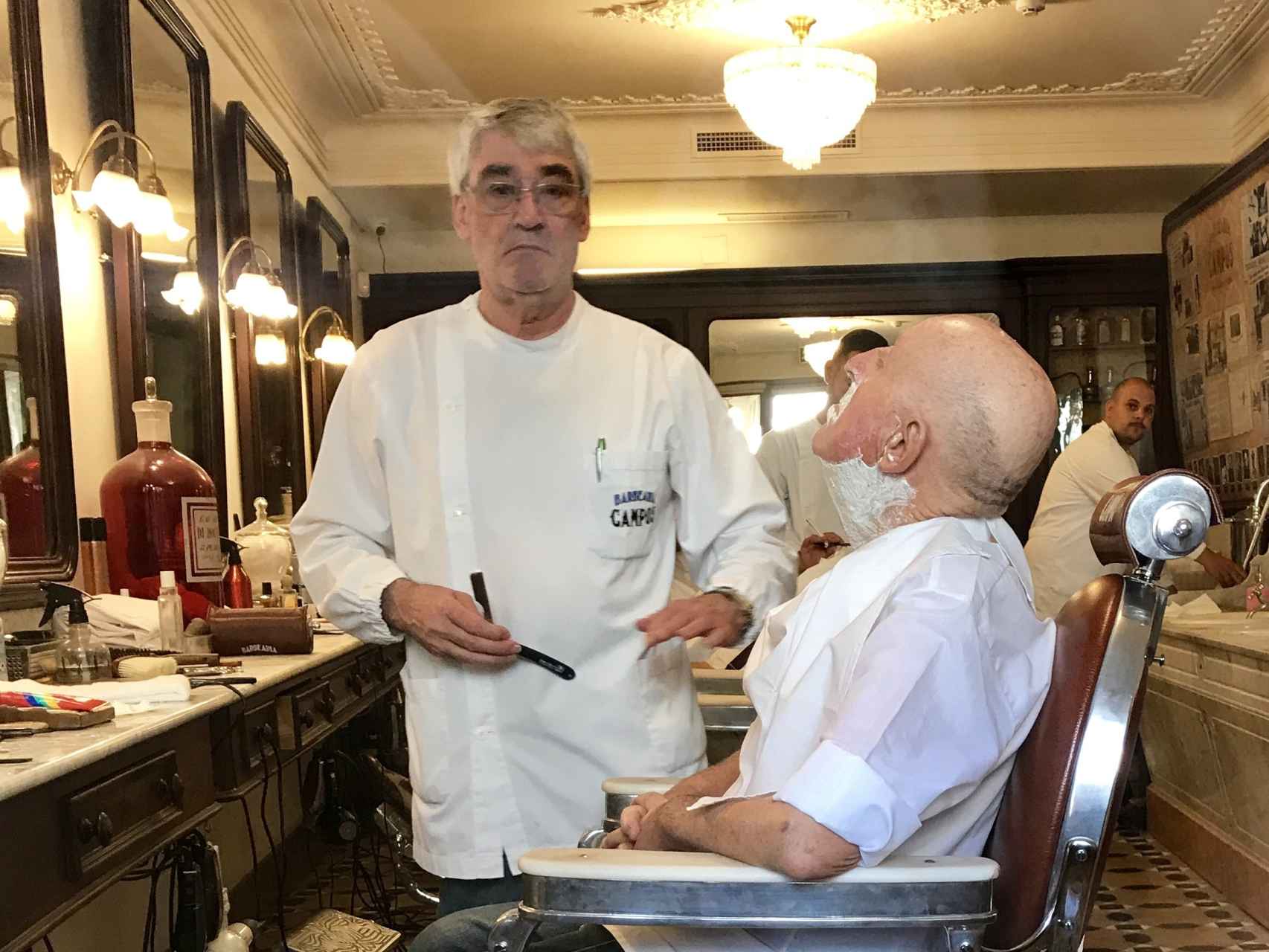 El peluquero posa mientras realiza su trabajo.