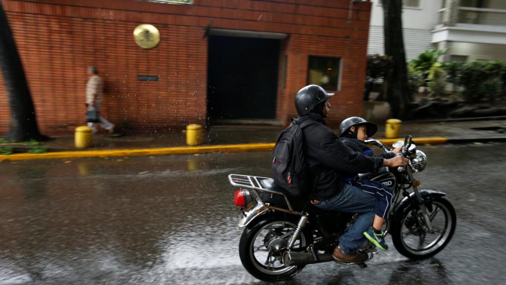 Un motorista pasa cerca de la embajada española en Caracas