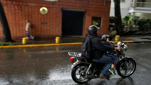 Un motorista pasa cerca de la embajada española en Caracas