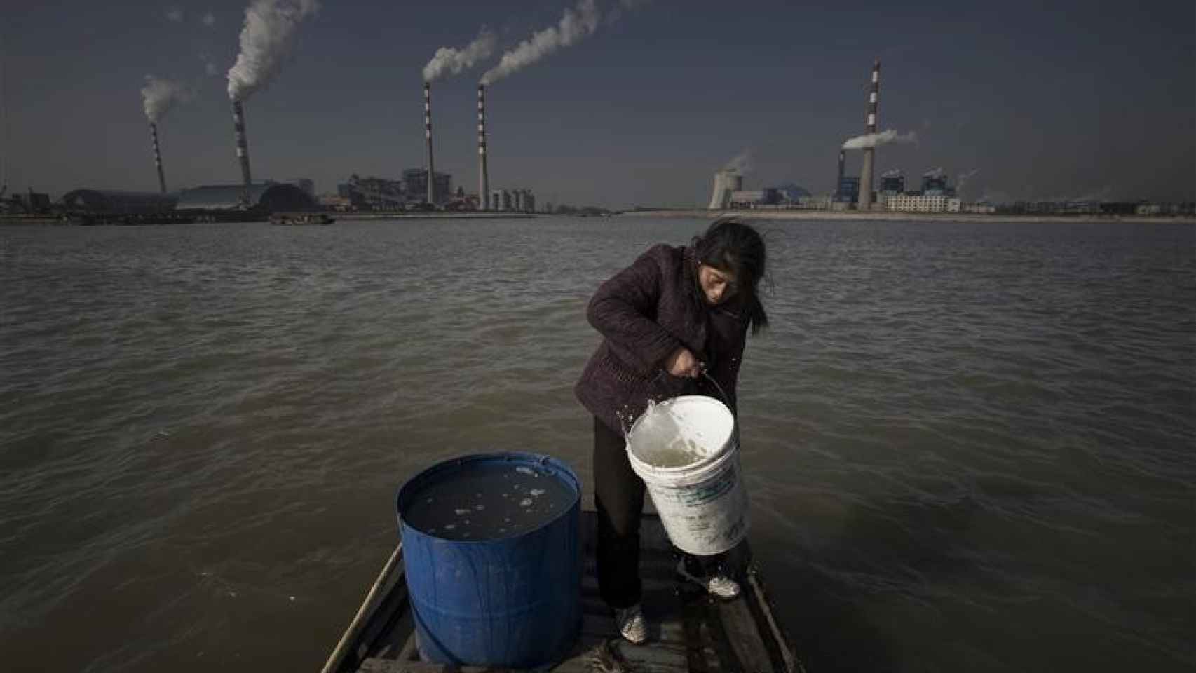 Una mujer recoge agua contaminada para consumo doméstico.