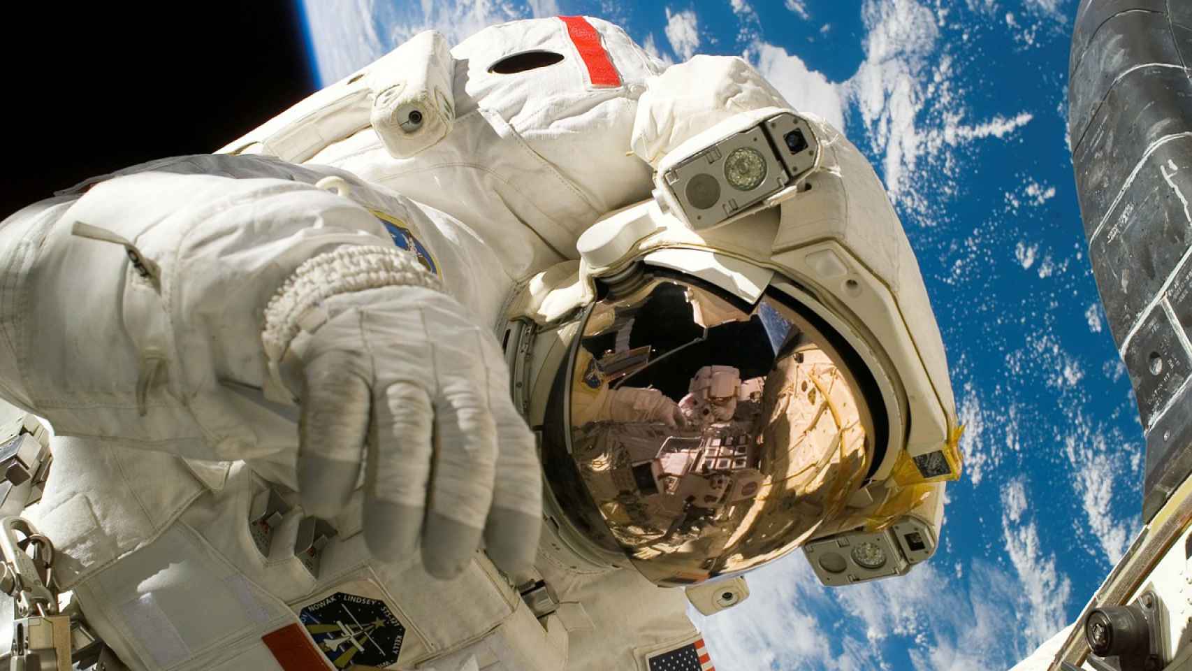 Un astronauta con traje blanco haciendo trabajos de mantenimiento en el espacio.