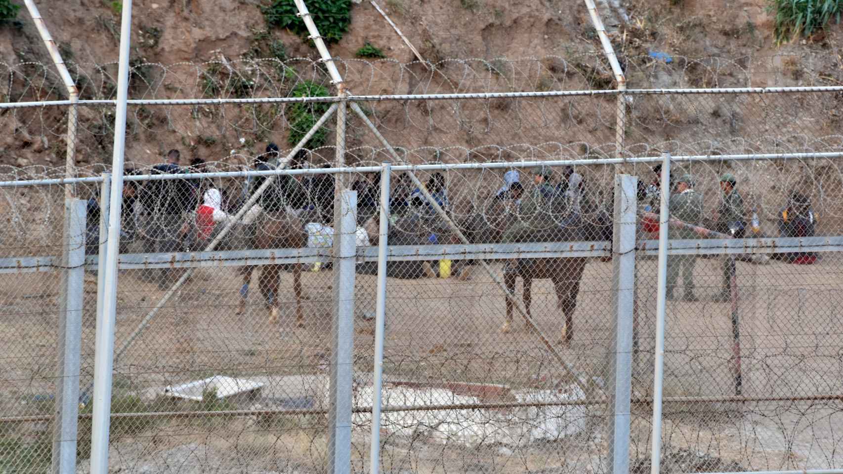 Un grupo de inmigrantes detenidos detrás de la valla.