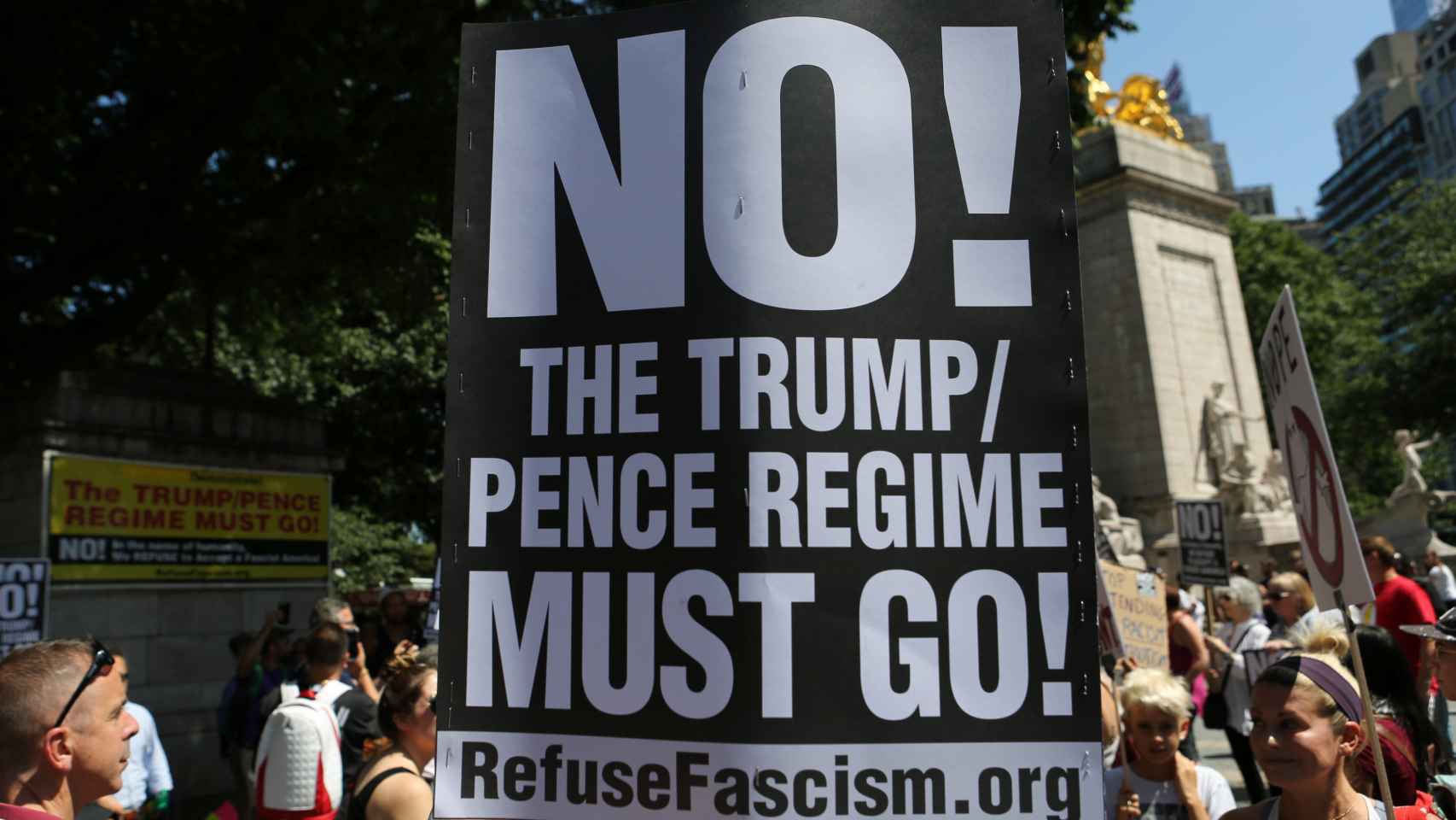 Uno manifestante expone un cartel contra lo que llama el régimen de Trump.