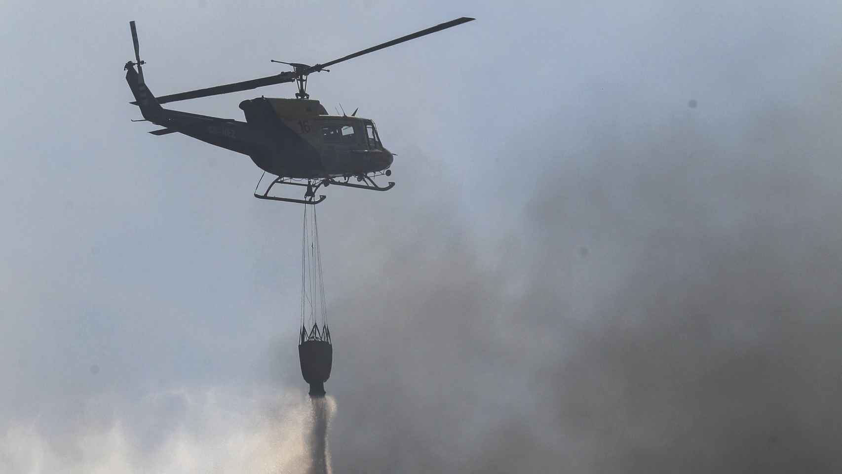 Un helicóptero descarga agua sobre un incendio forestal declarado en Portugal.