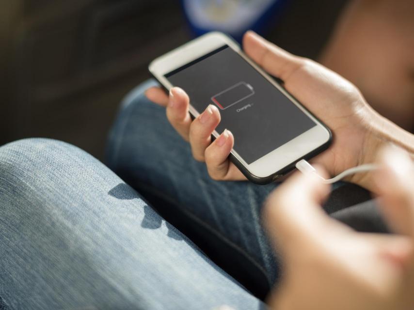 Una joven trata de cargar la batería agotada de su teléfono móvil.