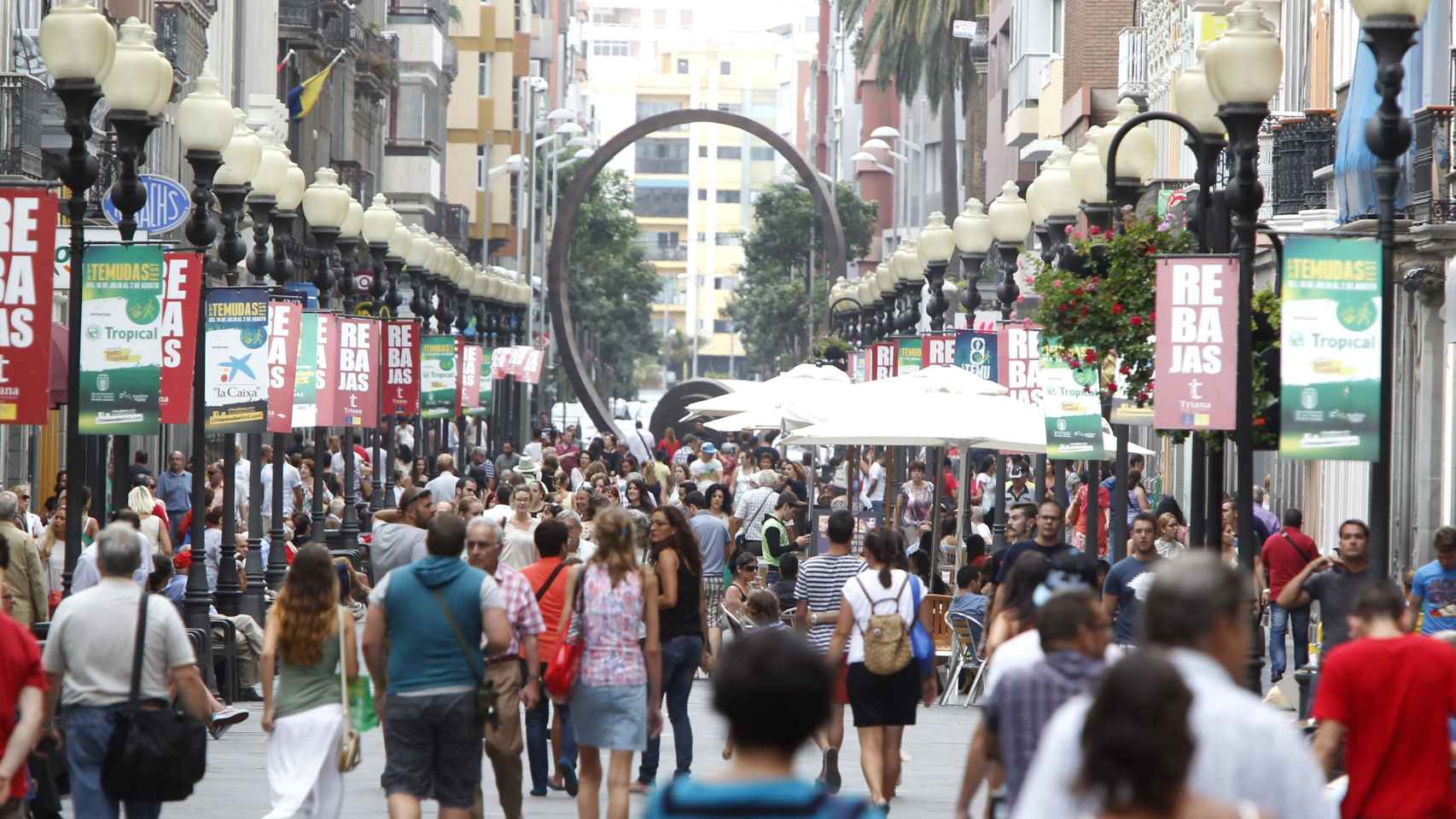 Varios viandantes pasean por el centro de una ciudad española.
