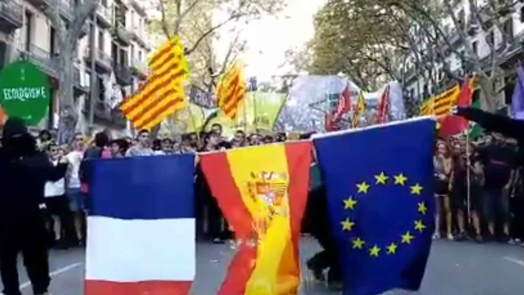 Dos encapuchados queman la bandera de España, de Francia y de la UE.