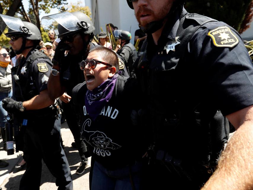 Los policías agarran a una persona en la manifestación.